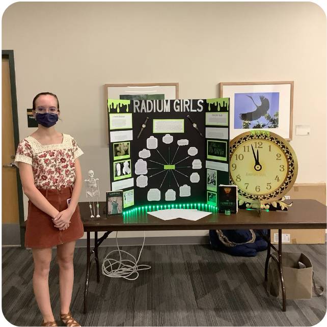 Student standing in front of her exhibit titled Radium Girls